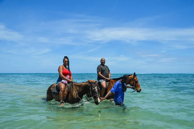 Tourists on horseback riding along a Jamaican beach on a horseback riding excursion near Ocho Rios Jamaica
